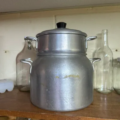 Sale Photo Thumbnail #136: Vintage aluminum double boiler set sitting on a wooden shelf alongside clear glass bottles.