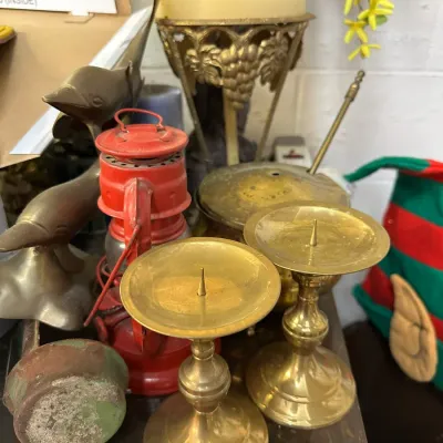 Sale Photo Thumbnail #37: Collection of brass and vintage decor, including a pair of brass pricket candlesticks, a small red lantern, and a brass dolphin figurine.