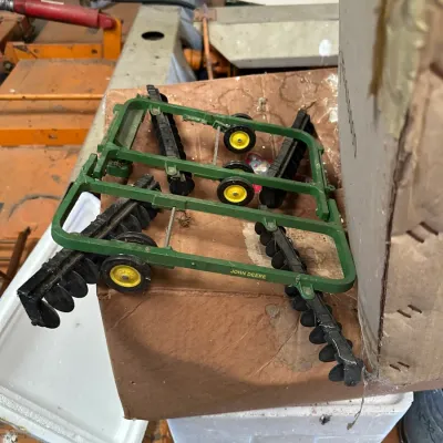 Sale Photo Thumbnail #205: Vintage Ertl John Deere toy disc harrow, featuring a green die-cast frame with yellow wheels and black plastic discs.