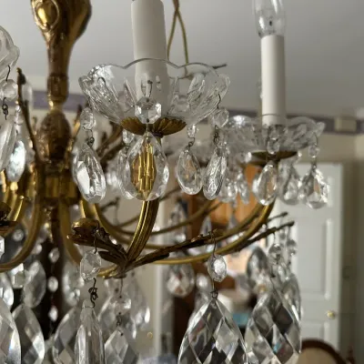 Sale Photo Thumbnail #455: Close-up detail of a vintage brass chandelier featuring scalloped glass bobeches and faceted glass crystal prisms.
