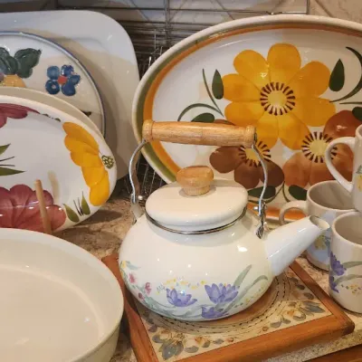Sale Photo Thumbnail #223: Collection of vintage floral dinnerware, including large serving platters, a white enamel teapot with wooden handles, matching floral mugs, and a baking dish.