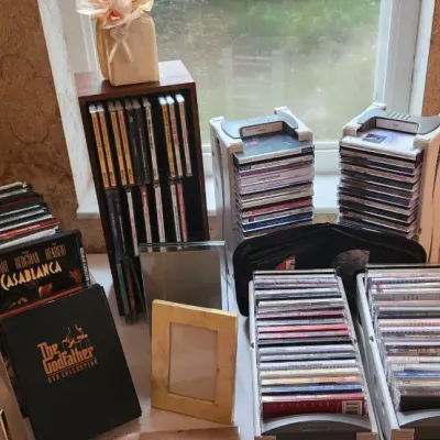Sale Photo Thumbnail #82: Collection of CDs and DVDs, including classic movie titles and storage racks, alongside various picture frames.
