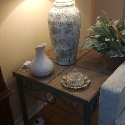 Sale Photo Thumbnail #151: Large textured urn-style table lamp with a beige drum shade, set on a metal-frame end table alongside decor items.