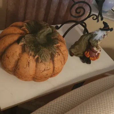 Sale Photo Thumbnail #40: Decorative Halloween pumpkin figure and a small witch figurine displayed on a white side table.