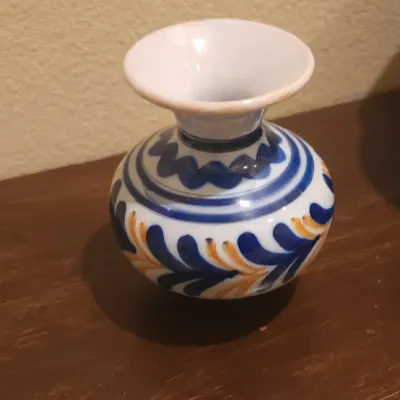 Sale Photo Thumbnail #130: Small hand-painted ceramic vase featuring blue and gold leaf motifs over a white glaze.