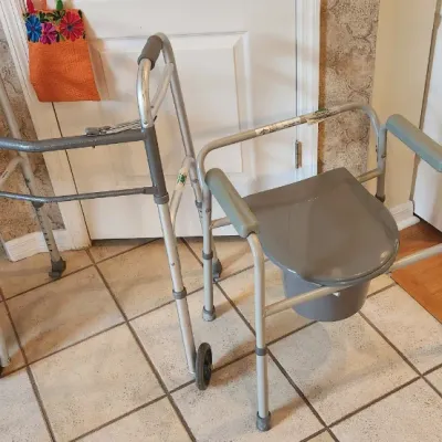 Sale Photo Thumbnail #123: Pair of medical assistance items including a height-adjustable folding walker with front wheels and a metal bedside commode chair.