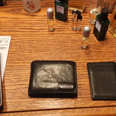 Sale Photo Thumbnail #98: Collection of men's personal items on an oak surface, including a black Tommy Hilfiger bifold leather wallet, Nautica card holder, VTech cordless phone, Sharp digital alarm clock, and various cologne bottles.