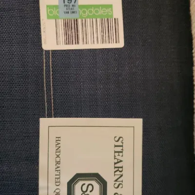 Sale Photo Thumbnail #262: Manufacturer tags on a Stearns & Foster sleeper sofa featuring dark blue textured fabric.