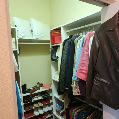 Sale Photo Thumbnail #60: Walk-in closet filled with women's clothing, shoes, and accessories, featuring a black leather jacket hanging in the foreground.