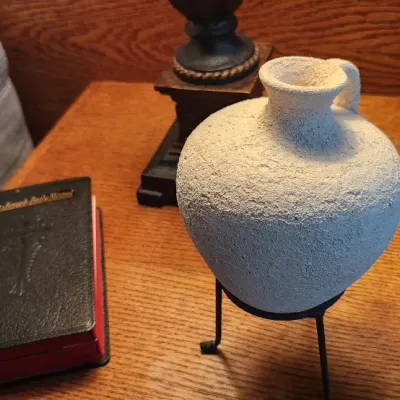 Sale Photo Thumbnail #108: Textured ceramic vessel displayed on a black metal stand alongside a Saint Joseph Daily Missal, resting on an oak nightstand.