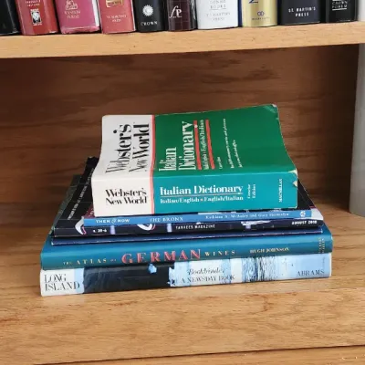 Sale Photo Thumbnail #270: Collection of art history and reference books, including Webster's New World Italian Dictionary and art monographs, displayed on a wooden shelf.