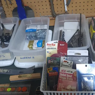 Sale Photo Thumbnail #363: Assortment of organized workshop hardware and tools including clear plastic storage bins labeled for wall anchors, clamps, screws, and nails.