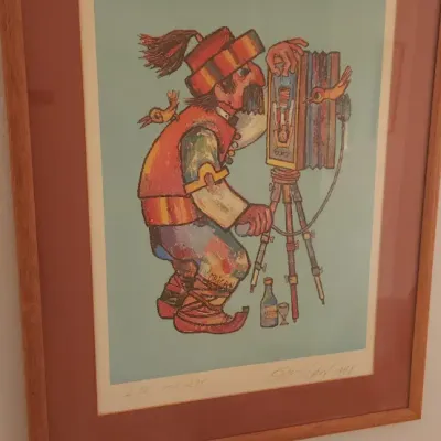 Sale Photo Thumbnail #170: Framed and matted artwork by Jovan Obican depicting a photographer with an accordion-style camera, pencil-signed and numbered in a simple wooden frame.