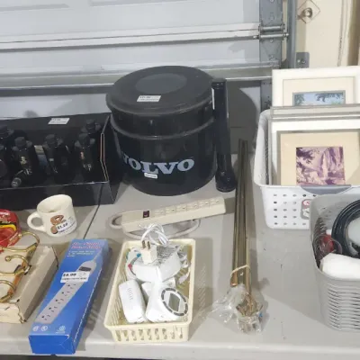 Sale Photo Thumbnail #342: Assortment of household items including Volvo branded accessories, power strips, small framed pictures, and various automotive and maintenance supplies.