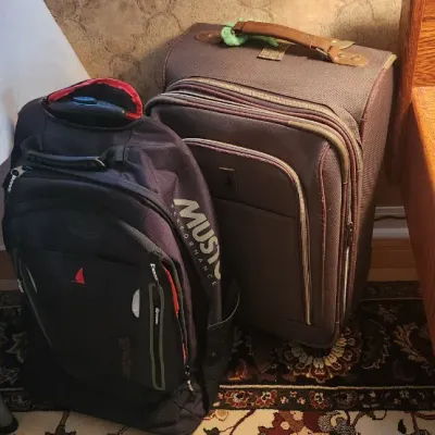 Sale Photo Thumbnail #88: Black Musto Performance backpack sitting beside a brown soft-sided wheeled suitcase.
