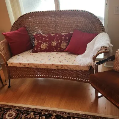 Sale Photo Thumbnail #103: A vintage woven wicker loveseat flanked by two mid-century chrome-framed armchairs upholstered in brown velvet.