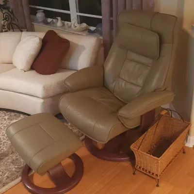 Sale Photo Thumbnail #17: Scandinavian-style leather recliner chair with matching ottoman, alongside a large curved sectional sofa and glass coffee table.
