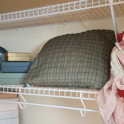 Sale Photo Thumbnail #291: Assorted home goods on wire shelving, including a vintage fabric clown doll, decorative throw pillows, small gift boxes, and a plush bird.
