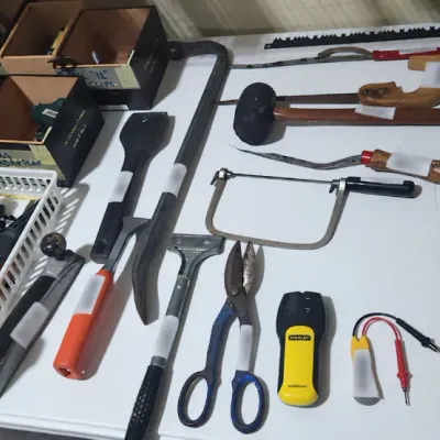 Sale Photo Thumbnail #379: Assortment of hand tools including saws, pry bars, snips, a Stanley stud finder, and organized hardware, arranged on a folding table.