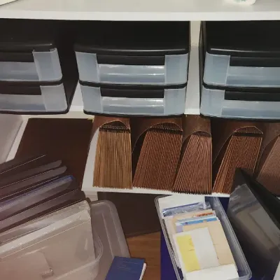 Sale Photo Thumbnail #289: Collection of office organization supplies, including three black two-drawer plastic organizers, brown expanding accordion files, and plastic storage bins containing papers and folders.