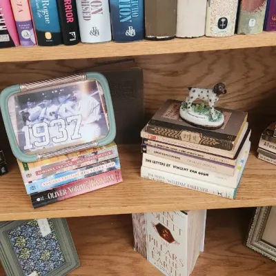 Sale Photo Thumbnail #268: Wooden bookshelf filled with stacks of vintage and contemporary books, framed sports art, and decorative tabletop accents.