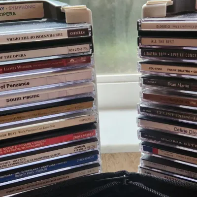 Sale Photo Thumbnail #87: Two portable plastic CD storage towers filled with various compact discs, labeled for Broadway/Opera and Pop genres.