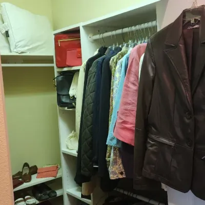 Sale Photo Thumbnail #61: Dark brown leather blazer hanging on a door, with additional women's clothing, handbags, and shoes organized inside a closet.
