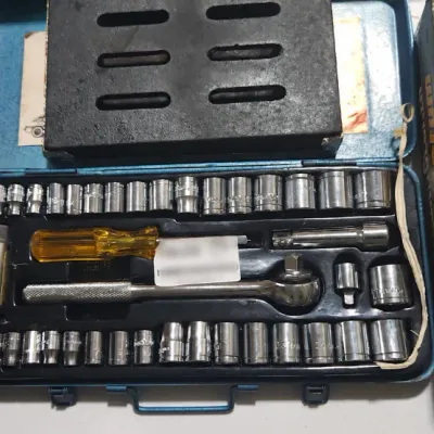 Sale Photo Thumbnail #382: Vintage mechanic's socket set in a blue metal case, featuring a ratchet handle, driver, and various socket sizes alongside power tool accessories.