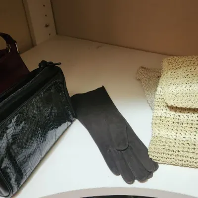 Sale Photo Thumbnail #73: Collection of vintage ladies' accessories, including a burgundy leather handbag, a black snakeskin-embossed purse, a black glove, and a woven straw clutch.