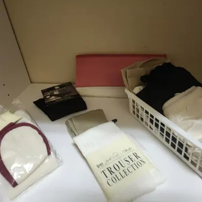 Sale Photo Thumbnail #56: Assortment of women's packaged hosiery, socks, and undergarments organized on a white closet shelf.