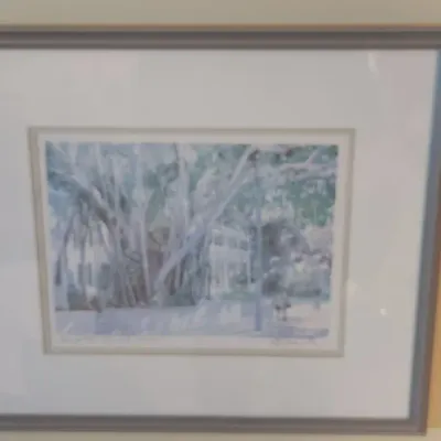 Sale Photo Thumbnail #34: Framed watercolor print depicting banyan trees in front of a Southern-style home, set under a wide mat in a grey wooden frame.