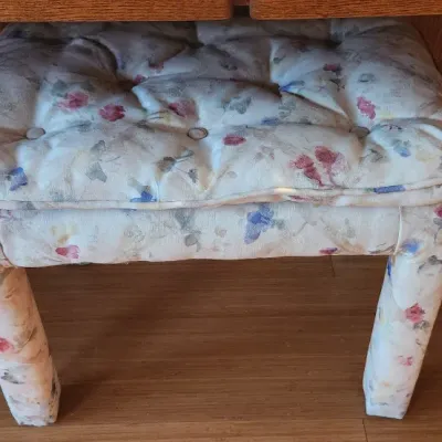 Sale Photo Thumbnail #102: Upholstered vanity stool featuring a floral fabric cover and a tufted seat cushion, tucked under a wooden desk.