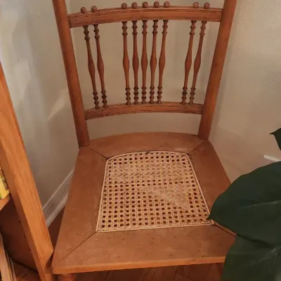 Sale Photo Thumbnail #264: Antique wooden side chair featuring a carved crest rail, spindle back, turned legs, and a cane seat insert.