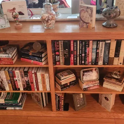 Sale Photo Thumbnail #263: Large wooden bookcase filled with various hardback and paperback books, decorative picture frames, figurines, and home accents.