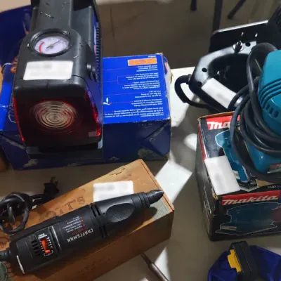 Sale Photo Thumbnail #375: Collection of power tools and shop equipment, including a Makita finishing sander in box, Craftsman rotary tool, portable air compressor, and a DeWalt circular saw blade.