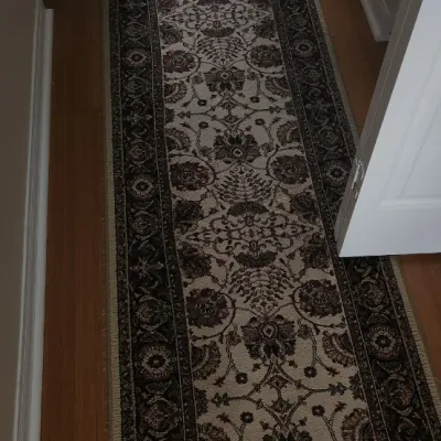 Sale Photo Thumbnail #113: Traditional Persian-style runner rug with an intricate floral motif in shades of burgundy, beige, and black on a hallway wood floor.