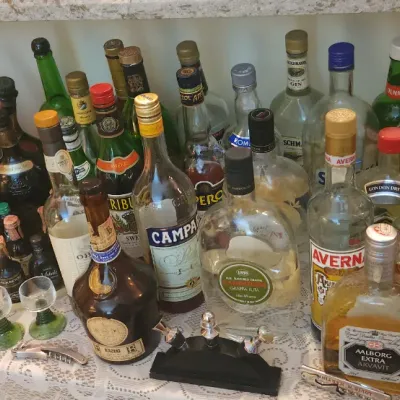 Sale Photo Thumbnail #147: Large collection of vintage liquor and liqueur bottles displayed alongside bar accessories, glassware, and novelty figures.