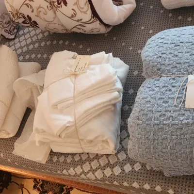 Sale Photo Thumbnail #105: Assorted folded bed linens, including a blue waffle-weave blanket and white sheet sets tied with twine.