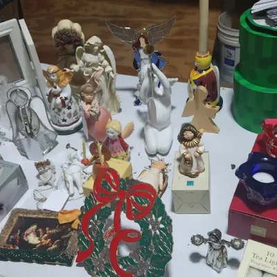 Sale Photo Thumbnail #327: Large assortment of holiday decor, including ceramic and glass angel figurines, Santa statues, votive holders, picture frames, and a green metal wreath.
