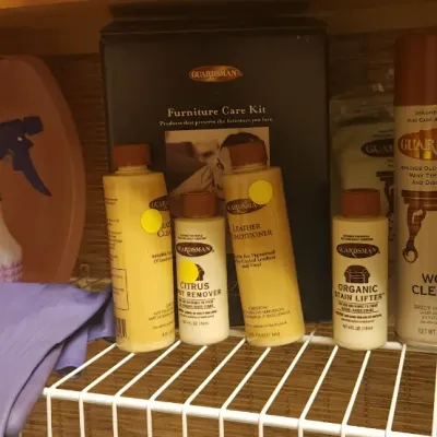 Sale Photo Thumbnail #250: Collection of cleaning supplies including Guardsman furniture care and leather products, spray bottle, rubber gloves, and a wash basin on wire shelving.