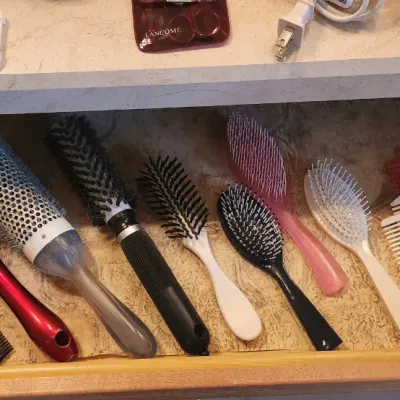 Sale Photo Thumbnail #125: Open vanity drawer filled with various modern hairbrushes, round styling brushes, and plastic combs.