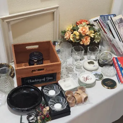 Sale Photo Thumbnail #127: Tabletop display featuring small glassware, vintage travel maps, a wooden storage crate, artificial flowers, and miscellaneous home decor items.