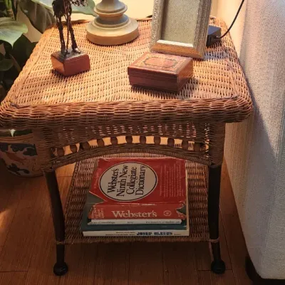 Sale Photo Thumbnail #257: Wicker side table with a lower storage shelf, featuring wood leg accents and spindle details.