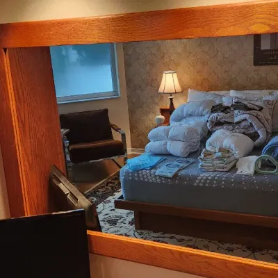 Sale Photo Thumbnail #96: Large solid oak dresser mirror reflecting a bedroom with linens and bedding stacked on a mattress.