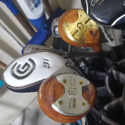 Sale Photo Thumbnail #348: Assorted vintage and modern golf clubs in a golf bag, including Wilson wooden drivers.