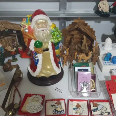Sale Photo Thumbnail #339: Collection of holiday decorations, featuring a large Santa Claus figurine, nativity scenes, plush Santas, boxed ornaments, and various Christmas collectibles.