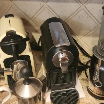 Sale Photo Thumbnail #217: Collection of kitchen appliances including Nespresso espresso makers, a toaster oven, electric milk frother, teapot, and coffee accessories.