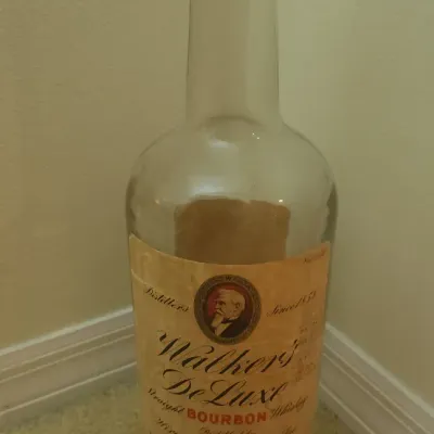 Sale Photo Thumbnail #323: Vintage Walker's DeLuxe Straight Bourbon Whiskey clear glass bottle with original paper label, distilled by Hiram Walker & Sons Inc.