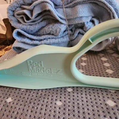 Sale Photo Thumbnail #111: Bed MadeEZ mattress lifter tool in light green plastic, shown alongside folded linens and blankets.