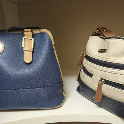 Sale Photo Thumbnail #71: Two women's handbags including a navy blue Giani Bernini satchel with tan trim and a multi-zippered cream and navy shoulder bag, both in good condition.